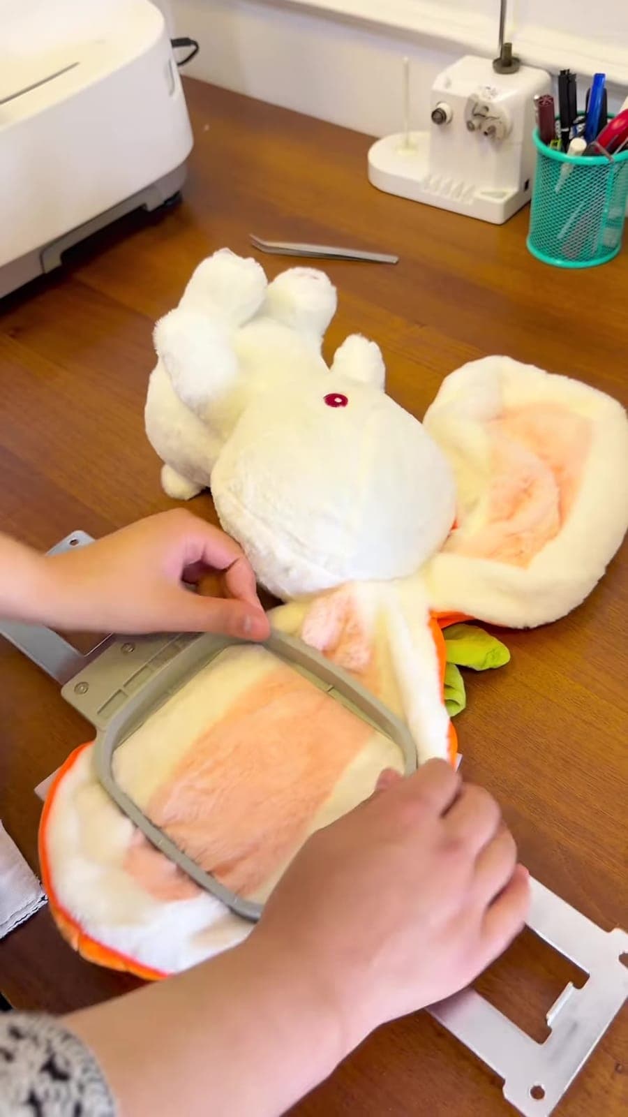 Mise en place de l'oreille de la peluche dans le cadre de broderie